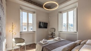 Un dormitorio moderno con una cama grande, una silla, un televisor y una lámpara de pie.