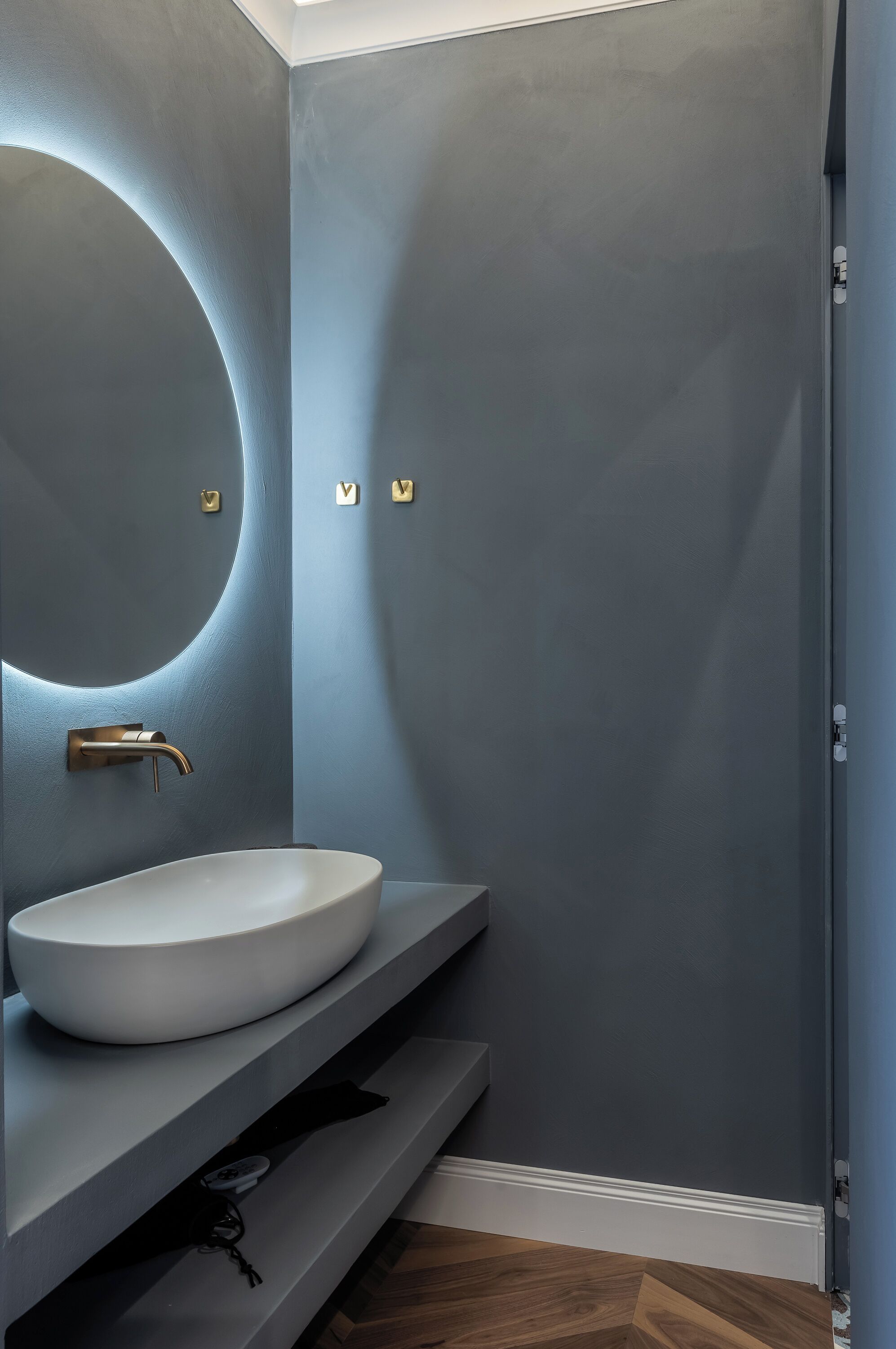 Een badkamer met een wit wastafel, een gebogen spiegel en een moderne kraan.