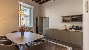 Una cocina moderna con comedor, que incluye una mesa de madera, sillas, horno empotrado y microondas.