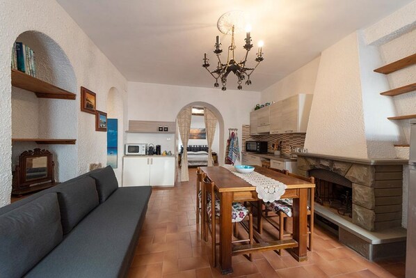 A cozy living room with a sofa, a dining table, and a fireplace.