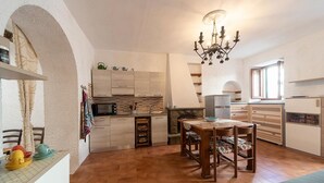 A compact kitchen with a dining area, a chandelier, and a fireplace.