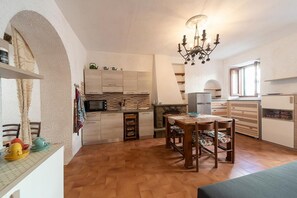 A compact kitchen with a dining area, a chandelier, and a fireplace.