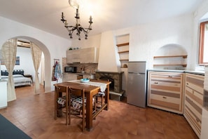 A compact kitchen with a dining table, a chandelier, and a refrigerator.