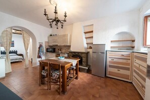 Une cuisine de taille réduite comprenant une table à manger, un lustre et un réfrigérateur.