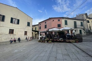 Une place publique avec un café, un pavage en pierre et des bâtiments historiques.