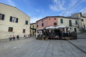 A public square with a café, stone pavement, and historic buildings.