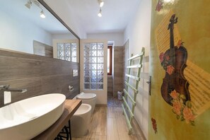 A bathroom with a large oval sink, a toilet, and a window with frosted glass.