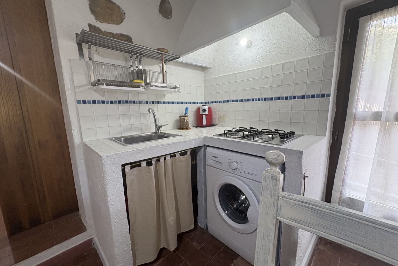 A compact kitchen with a washing machine, a gas stove, and a sink.
