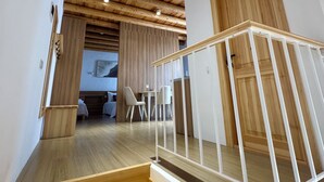 A wooden staircase with a white railing leading to a room with a wooden ceiling and a door.