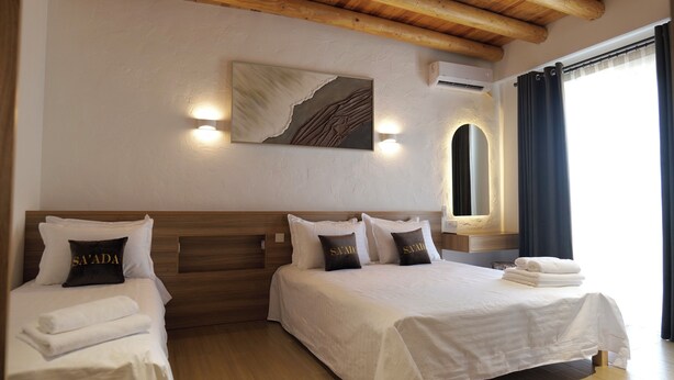 A hotel room with two beds, a wooden ceiling, a painting on the wall, and a window with curtains.