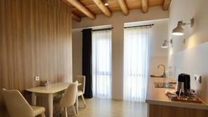 A modern kitchen with a wooden ceiling, a dining area with a table and chairs, and a counter with a coffee maker.