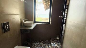 Un baño con inodoro, lavabo y ventana con vistas a la playa.