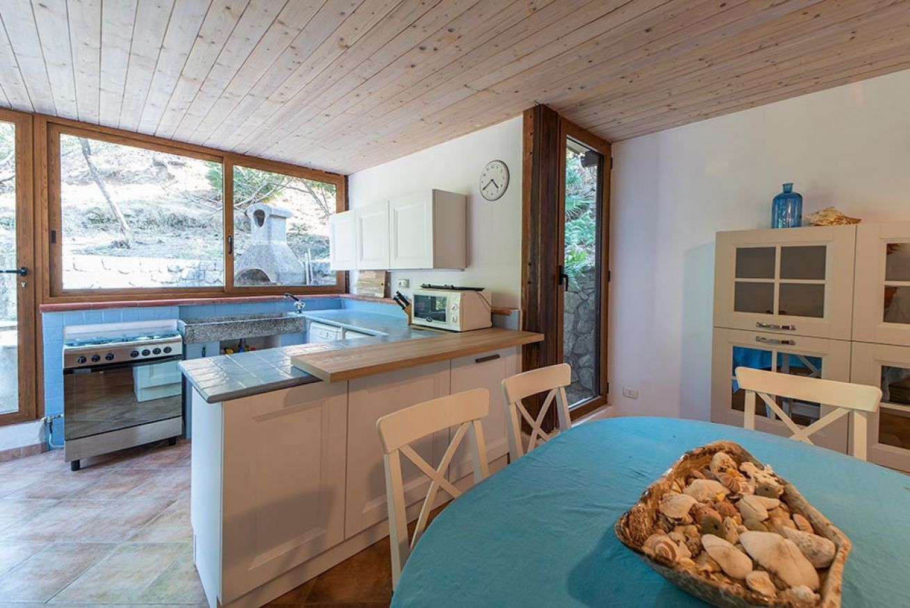 A compact kitchen with a stove, sink, and a dining area with a table and chairs.