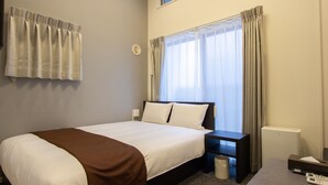 A hotel room with a bed, bedside table, and a window with curtains. - HOTEL FAMILIA Hakata East (Fukuoka)