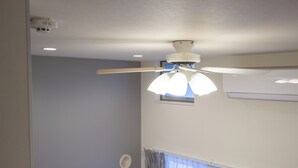 A ceiling fan with lights, a window with curtains, and a wall-mounted air conditioning unit. - HOTEL FAMILIA Hakata East (Fukuoka)