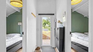A narrow hallway with two beds on either side, a refrigerator, and a door leading outside.