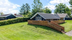 A row of modern, single-story cabins with a sloped roof, surrounded by well-maintained lawns and a wooden fence.