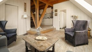 Une pièce de style « loft », avec des poutres en bois apparentes, une table à manger agrémentée d’un vase et deux fauteuils rembourrés.