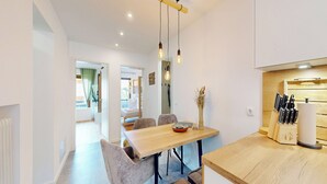 Une cuisine moderne avec un plan de travail en bois, une table à manger avec des chaises et des luminaires suspendus.