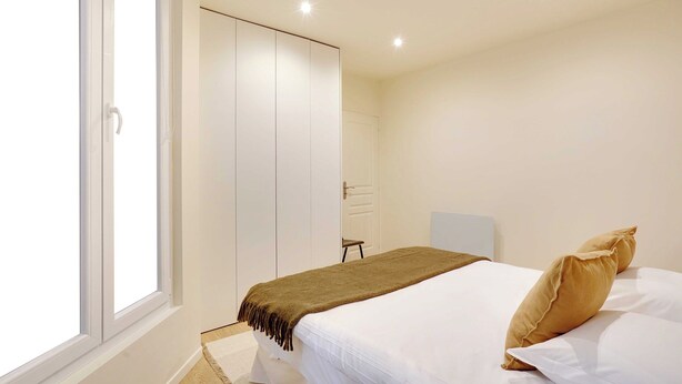 Ein Schlafzimmer mit Bett, Fenster, Kleiderschrank und Nachttisch.