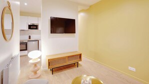Ein modernes Wohnzimmer mit einer Holzbank, einem runden Tisch und einem an der Wand befestigten Flachbildfernseher.