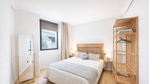A bedroom with a bed, bedside tables, a window with curtains, a wooden wardrobe, and a door. - Sea View - 2 Bedrooms - Pet Friendly - Ideal for Families - Noia (Noia)