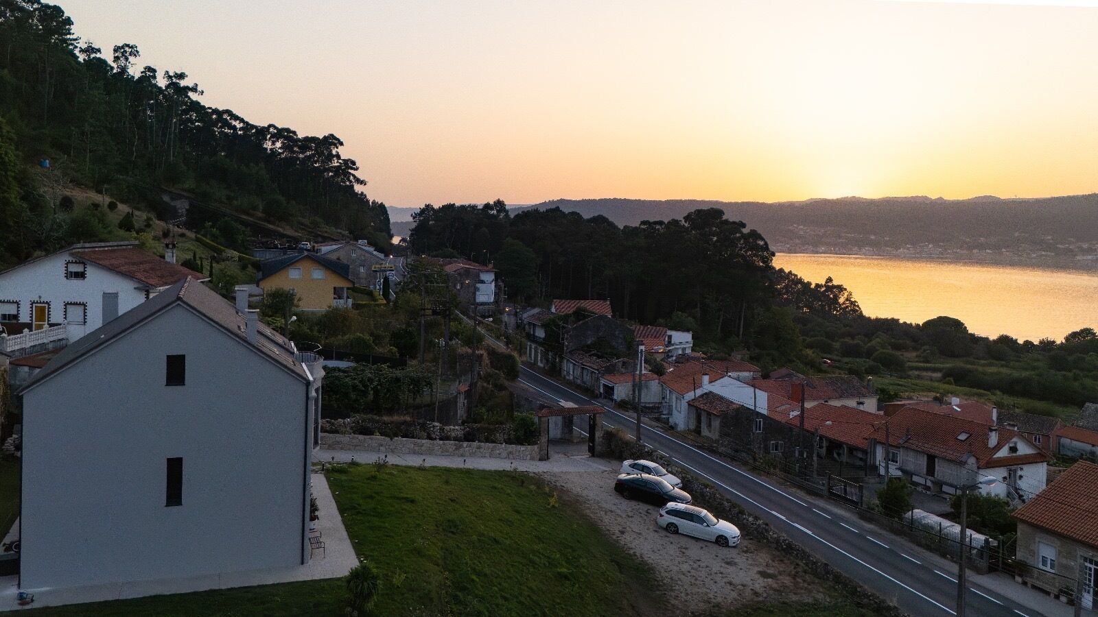 Zona residencial con casas, una carretera y una masa de agua al fondo.