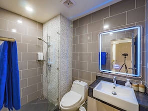 Une salle de bain moderne avec une douche à parois de verre, des toilettes, un lavabo avec un miroir et une serviette bleue suspendue à un porte-serviettes.