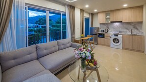 Una sala moderna con un sofá, una mesa de comedor con sillas, una cocina equipada y un amplio ventanal con cortinas.