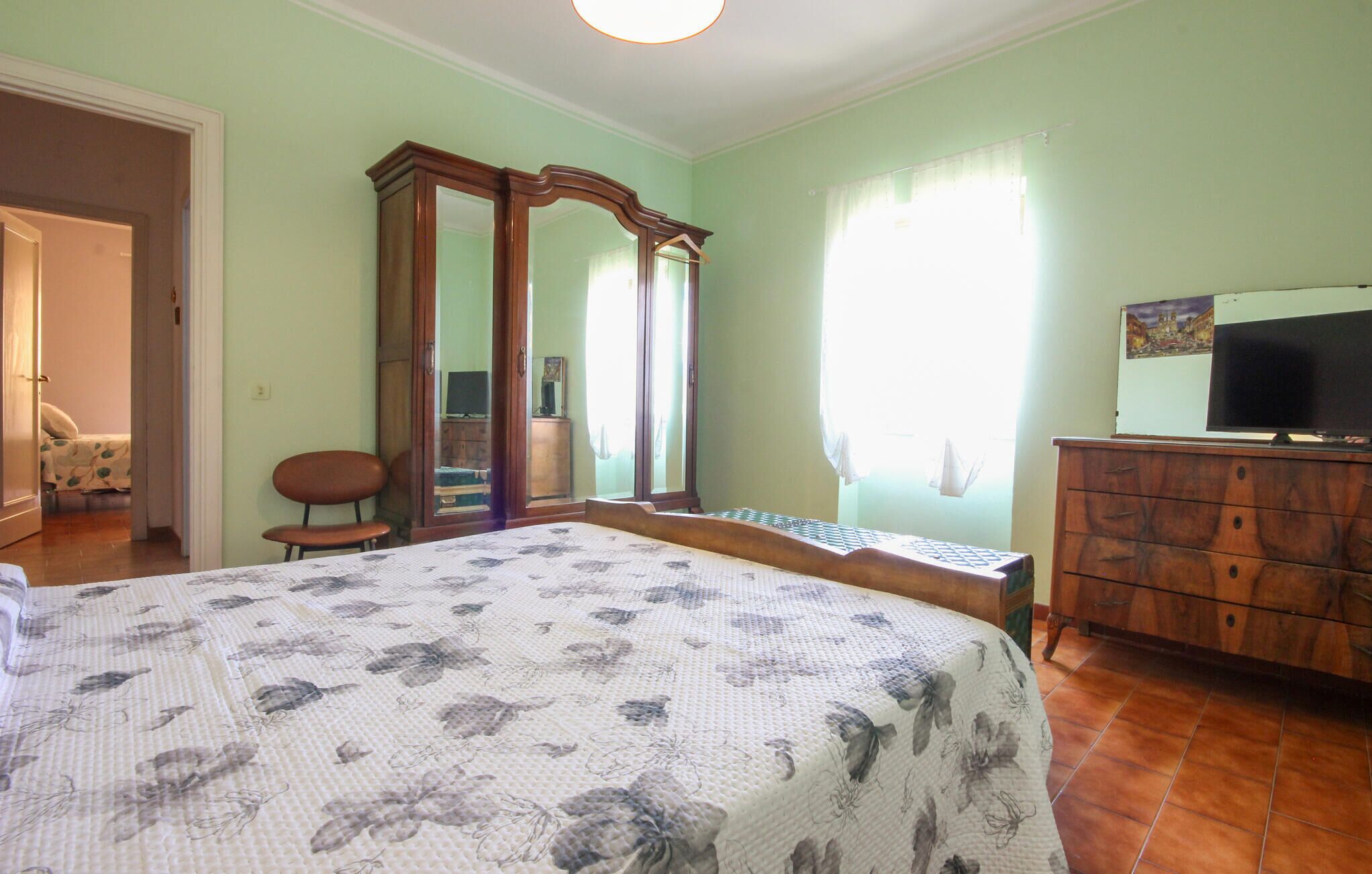 A bedroom with a bed, a dresser, a television, and a wardrobe.