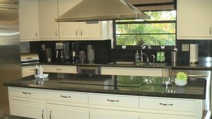 A modern kitchen with white cabinets, a black countertop, and a window with a view of greenery. - PGA National Luxury Estate Home, Golf and Lake, Discount @ 3+ weeks (Palm Beach Gardens)