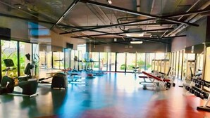 A spacious gym with cardio machines, weight benches, and dumbbells.