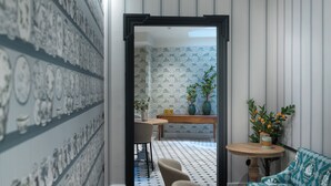 Een kamer met behang met een patroon, een eethoek met een tafel en stoelen, en een bank.