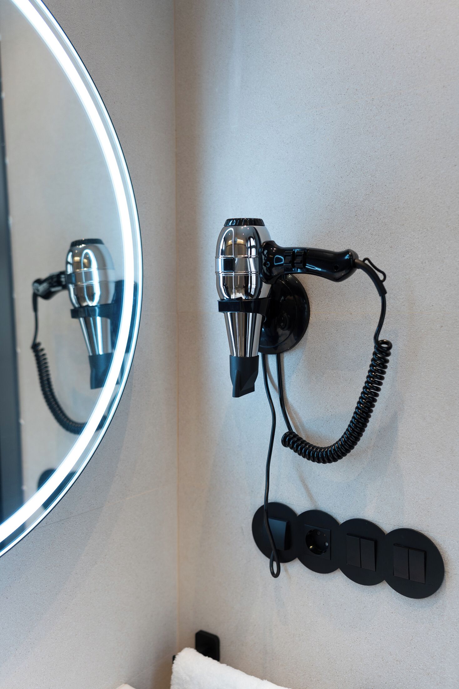 A hairdryer mounted on a wall with a mirror above it.