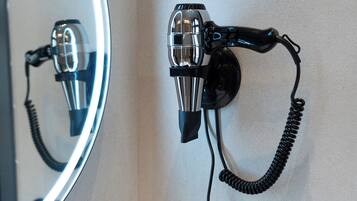 A hairdryer mounted on a wall with a mirror above it.