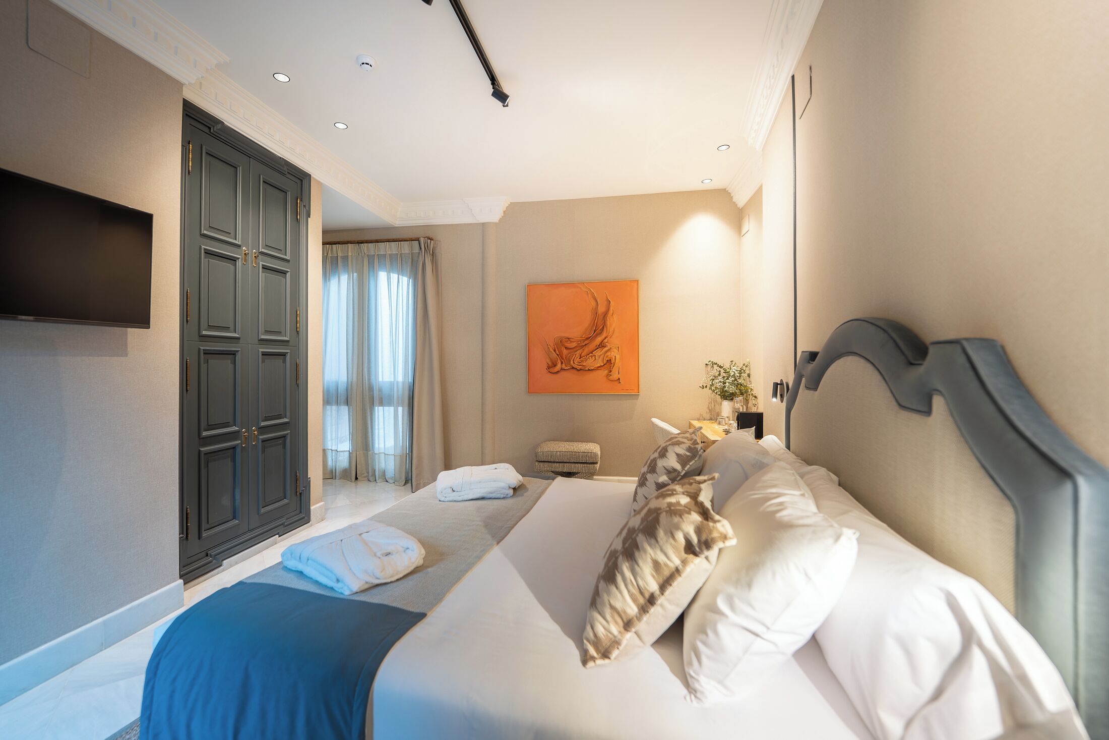 Un cuarto de hotel con una cama grande, un televisor de pantalla plana en la pared, un cuadro y vistas al exterior a través de la ventana.
