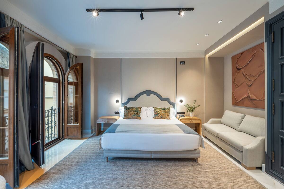 Een moderne hotelkamer met een groot bed, een bank en een decoratieve wand.