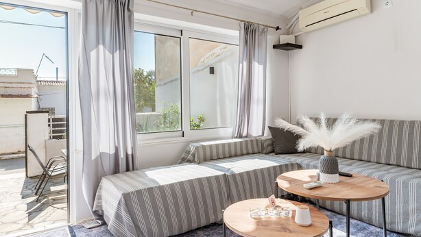 A modern room with a sofa, a round wooden table, and a view through a large window. - Country House 'Azure Nest' with Private Terrace, Wi-Fi, and Air Conditioning (Nea Peramos)