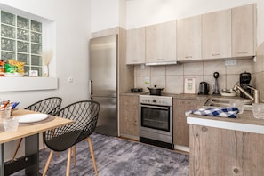 Eine moderne Küche mit Holzschränken, einem Edelstahlkühlschrank, einem Einbauofen und einer Kaffeemaschine.