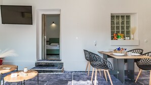 A modern kitchen with a dining area, a TV mounted on the wall, and a window with a view. - Country House 'Azure Nest' with Private Terrace, Wi-Fi, and Air Conditioning (Nea Peramos)