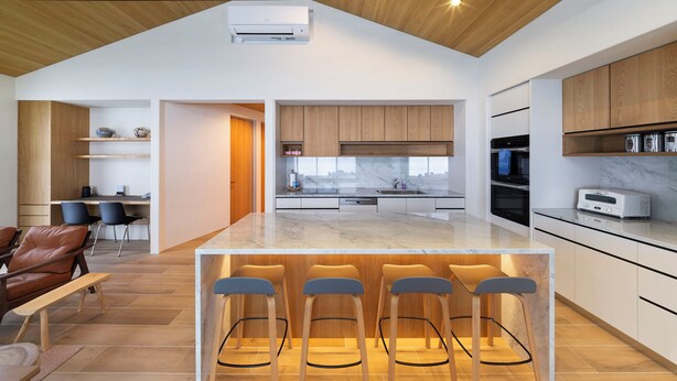 A modern kitchen with a central island, wooden cabinets, and a marble countertop. - Sakuraya (Hakuba)