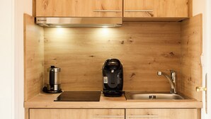 A compact kitchen with wooden cabinets, a built-in stove, a coffee maker, and a sink. - Quartier 7 apartment in a quiet location and access to the sea time (Büsum)