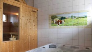 A wooden sauna with a window, a hot tub with rocks, and a mural of cows on a green field. - Gîte l'Essentiel, farmhouse group accommodation with spa and sauna, playground (Arc-sous-Cicon)