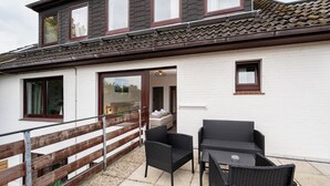 A two-story building with a balcony, wicker furniture, and a tiled roof. - Quartier 9 apartment in a quiet location and access to the sea time (Büsum)