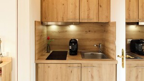 A compact kitchen with wooden cabinets, a Bosch coffee maker, a sink, and a vase with a red rose. - Quartier 9 apartment in a quiet location and access to the sea time (Büsum)