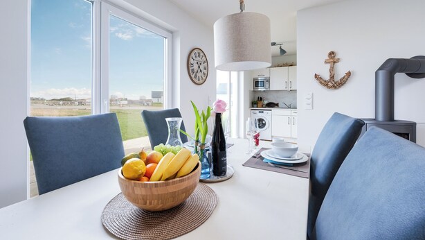 Una cocina moderna con un ventanal grande, una mesa de comedor con frutero y una lámpara colgante.