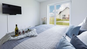 Un dormitorio con una cama grande, un televisor de pantalla plana en la pared y una puerta corrediza de vidrio que da a un patio.