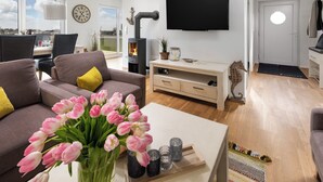 Una sala de estar moderna con un sofá, una mesa de centro con un jarrón de tulipanes, una chimenea y un televisor montado en la pared.