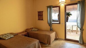 A room with two beds, a small table, and a view of the sea. - 2 bedroom lovely apartment in Briatico (Briatico)