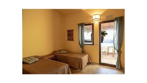 A room with two beds, a small table, and a view of the sea. - 2 bedroom nice apartment in Briatico (Briatico)